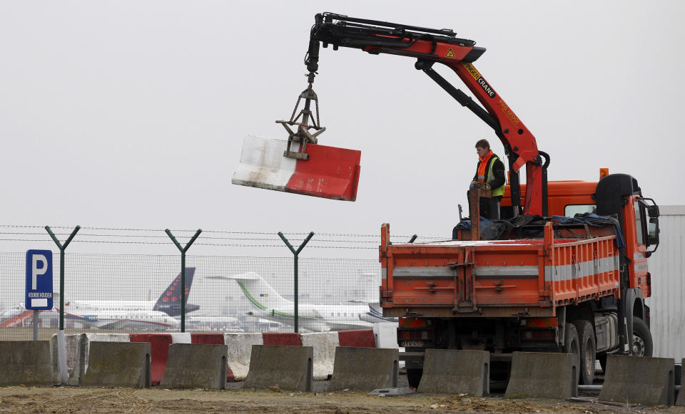 FILE - Workers place concrete blocks to block access made in a security fence next to the tarmac at Brussels international airport, on Feb. 19, 2013. A decade after a brazen diamond heist at Brussels airport, it looks like a near-perfect crime. While one person was convicted to five years in prison and a small part of the loot — estimated at $50 million in 2013 — was recovered, the four remaining suspects were acquitted on appeal Wednesday March 8, 2023, leaving it unclear whether the mastermind will ever be found. (AP Photo/Yves Logghe, File)