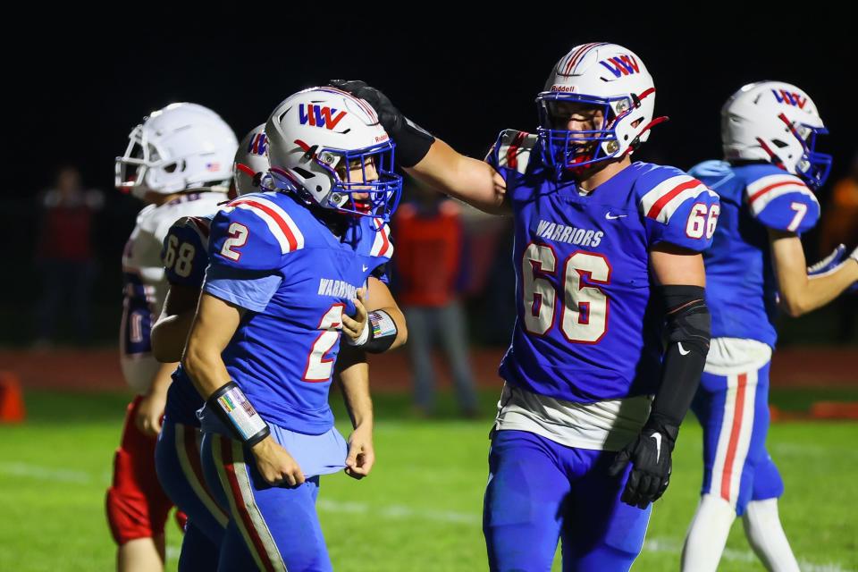 Winnacunnet's DJ Sciacca is congratulated by teammates Anthony Magri (68) and Owen Denio (66) after Sciacca scored a touchdown in the fourth quarter of last Friday's Division I football game. It was the first touchdown of the season for the Warriors.