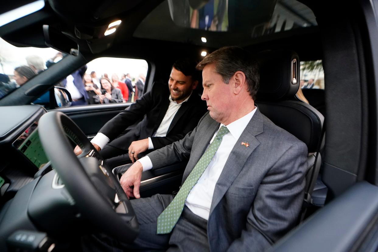 Georgia Gov. Brian Kemp, right, gets a tour of a Rivian electric truck from Rivian executive Vice President of facilities Jimmy Knauf during a ceremony to announce that the electric truck maker plans to build a $5 billion battery and assembly plant east of Atlanta projected to employ 7,500 workers, Thursday, Dec. 16, 2021, in Atlanta. (AP Photo/John Bazemore)