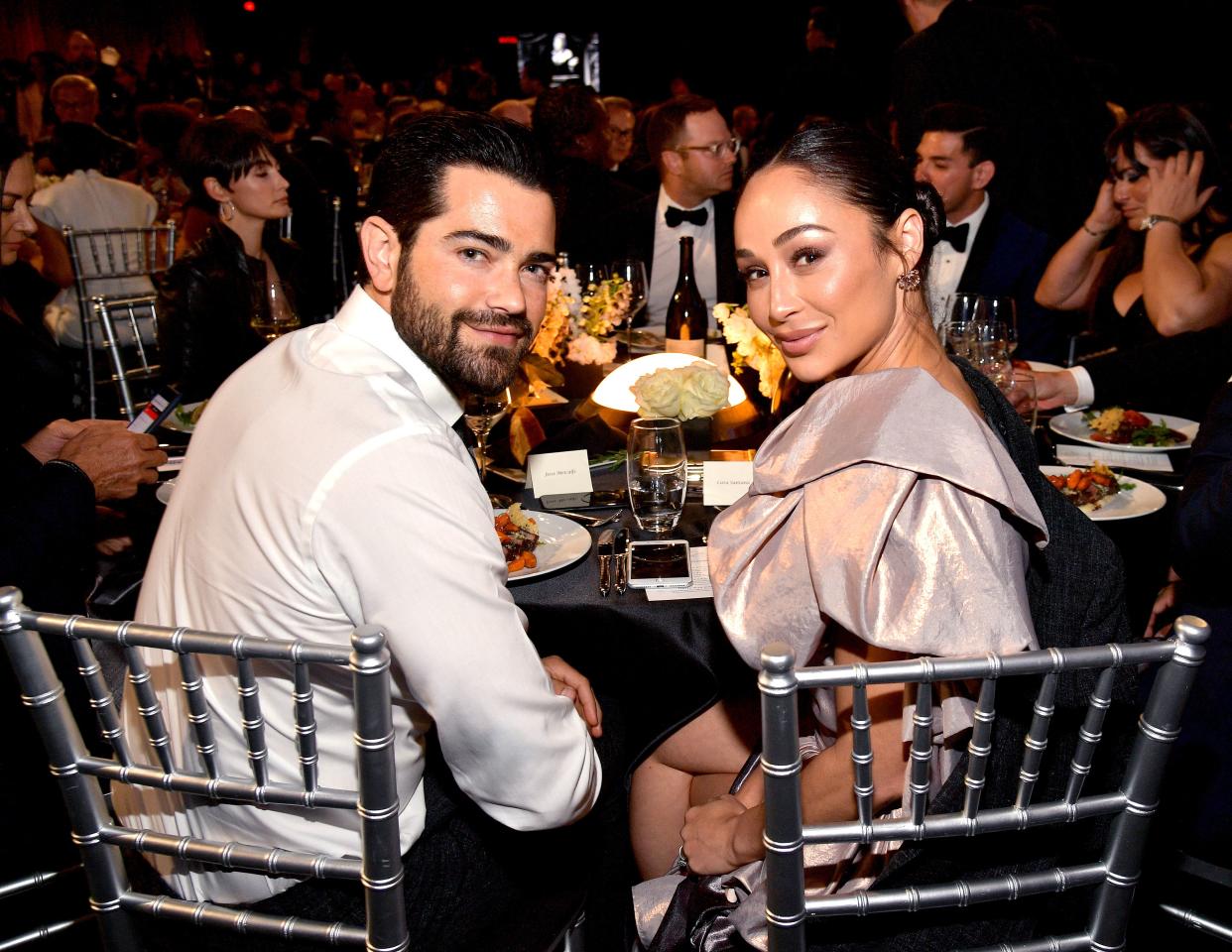 Jesse Metcalfe and Cara Santana sitting at a table at a dinner