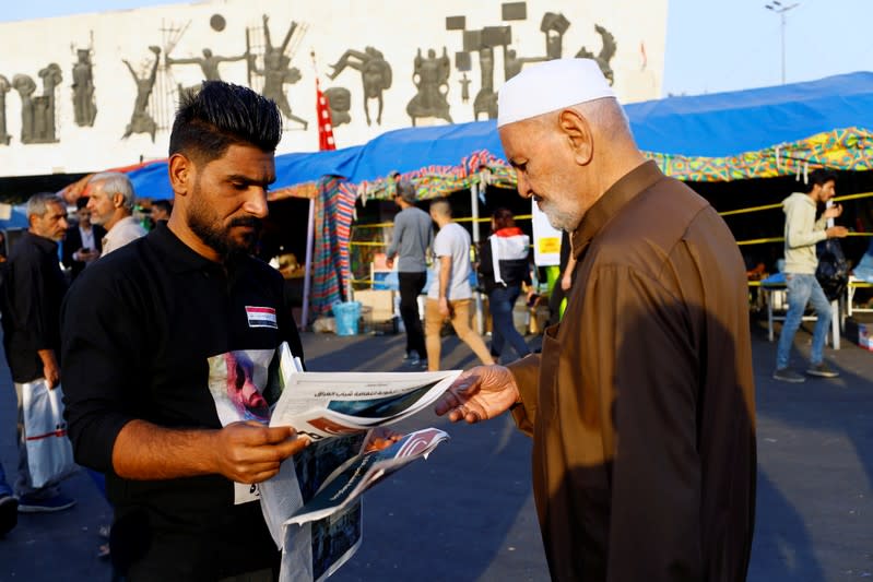 An Iraqi demonstrator distributes Tuktuk newspaper during the ongoing anti-government protests, in Baghdad