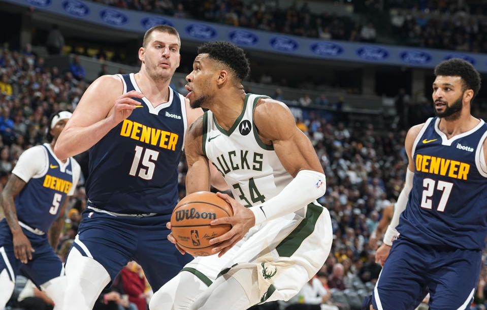 Giannis Antetokounmpo (34), de los Bucks de Milwaukee, intenta llegar a la canasta ante la presión de Nikola Jokic (15), de los Nuggets de Denver, y ante la mirada de Jamal Murray (27), en la segunda mitad del juego de baloncesto de la NBA, el lunes 29 de enero de 2024, en Denver. (AP Foto/David Zalubowski)