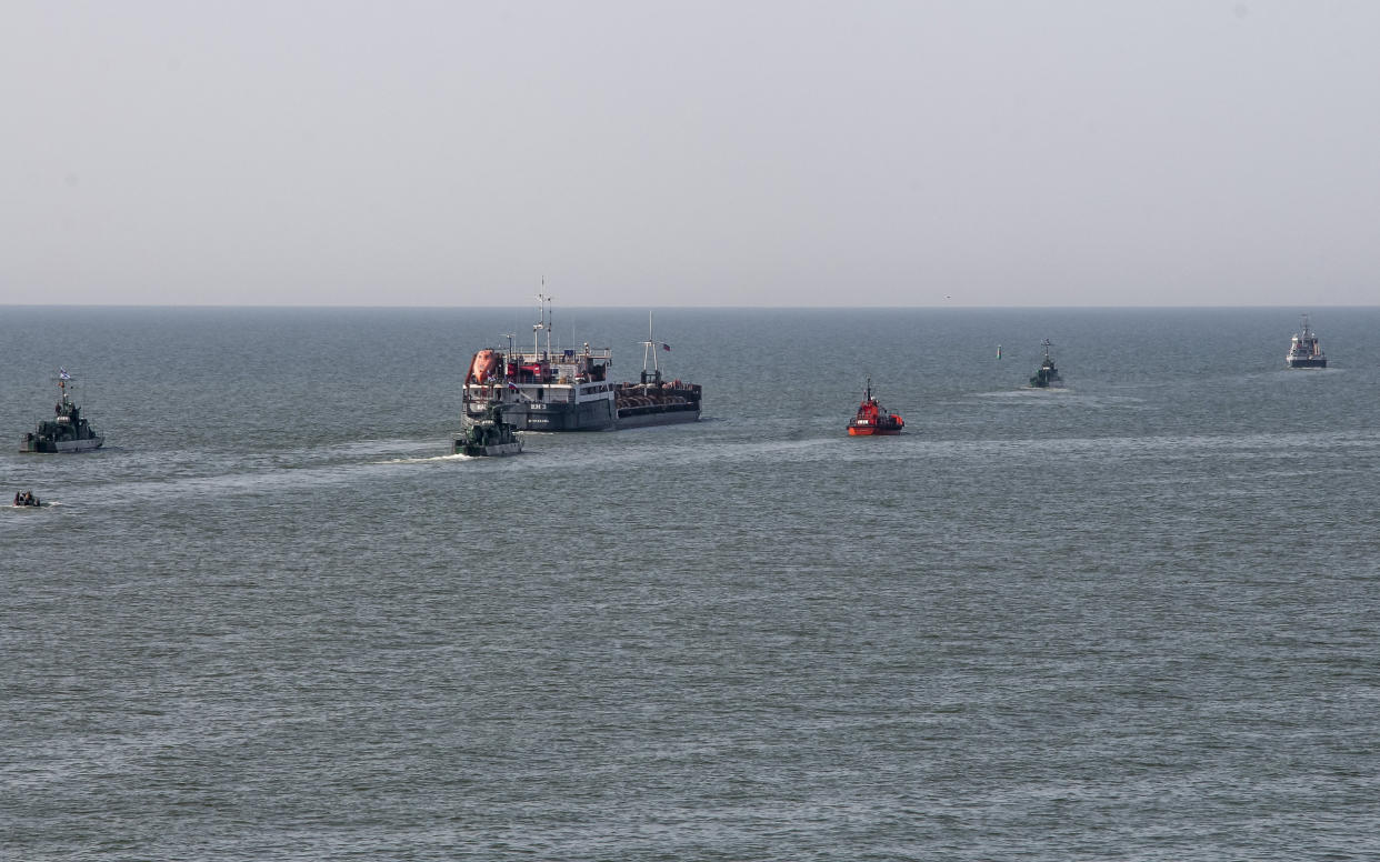 A Russian vessel, center, escorted by Russian military boats, departs from the port in Mariupol, Ukraine, on May 31, 2022. (AP)