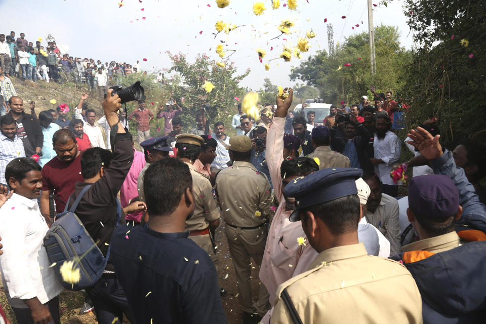 People throw flower petals on the Indian policemen guarding the area where rape accused were shot, in Shadnagar some 50 kilometers or 31 miles from Hyderabad, India, Friday, Dec. 6, 2019. An Indian police official says four men accused of raping and killing a woman in southern India have been fatally shot by police. (AP Photo/Mahesh Kumar A.)