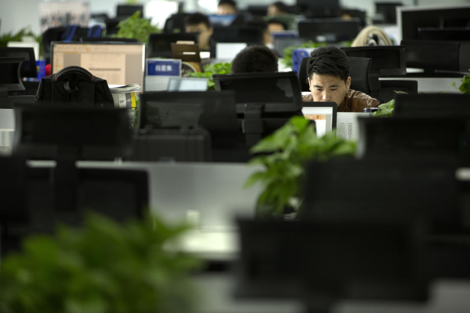 In this Oct. 31, 2018, photo, a Watrix employee works at his desk in their company's offices in Beijing. A Chinese technology startup hopes to begin selling software that recognizes people by their body shape and how they walk, enabling identification when faces are hidden from cameras. Already used by police on the streets of Beijing and Shanghai, “gait recognition” is part of a major push to develop artificial-intelligence and data-driven surveillance across China, raising concern about how far the technology will go. (AP Photo/Mark Schiefelbein)