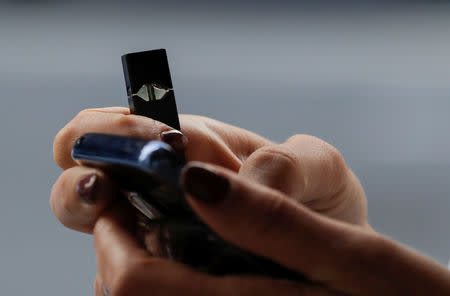 FILE PHOTO: A woman holds a Juul e-cigarette while walking in New York, U.S., September 27, 2018. REUTERS/Brendan McDermid