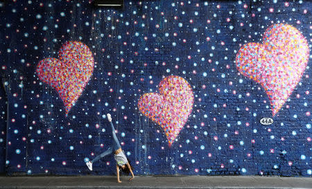 A girl does a cartwheel in front of a mural painted by James Cochran in memory of the victims of the London Bridge attack, on the anniversary of the attack, in London, Britain, June 3, 2018. REUTERS/Simon Dawson