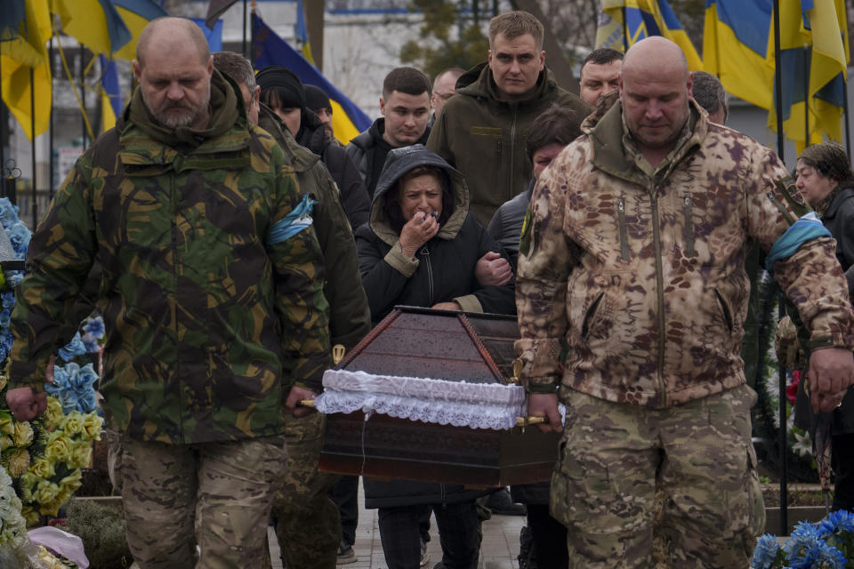 Servicemen carry the coffin of Ukrainian Cpt. Serhii Vatsko followed by his mother Oksana Vatsko in Boiarka, Ukraine, Friday, March 29, 2024. Vatsko, who was killed on the frontline of eastern Ukraine on March 24 joined the country's military in 2014. (AP Photo/Vadim Ghirda)