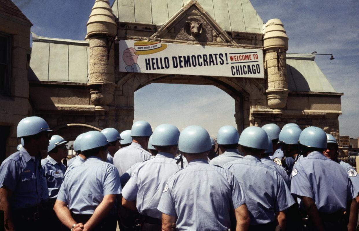 A sign welcomes delegates to the Democratic National Convention in 1968, with helmeted police officers standing by. <a href="https://www.gettyimages.com/detail/news-photo/the-sign-over-the-archway-leading-to-the-international-news-photo/515541970?searchscope=image%2Cfilm&adppopup=true" rel="nofollow noopener" target="_blank" data-ylk="slk:Bettmann/Getty Images;elm:context_link;itc:0;sec:content-canvas" class="link ">Bettmann/Getty Images</a>