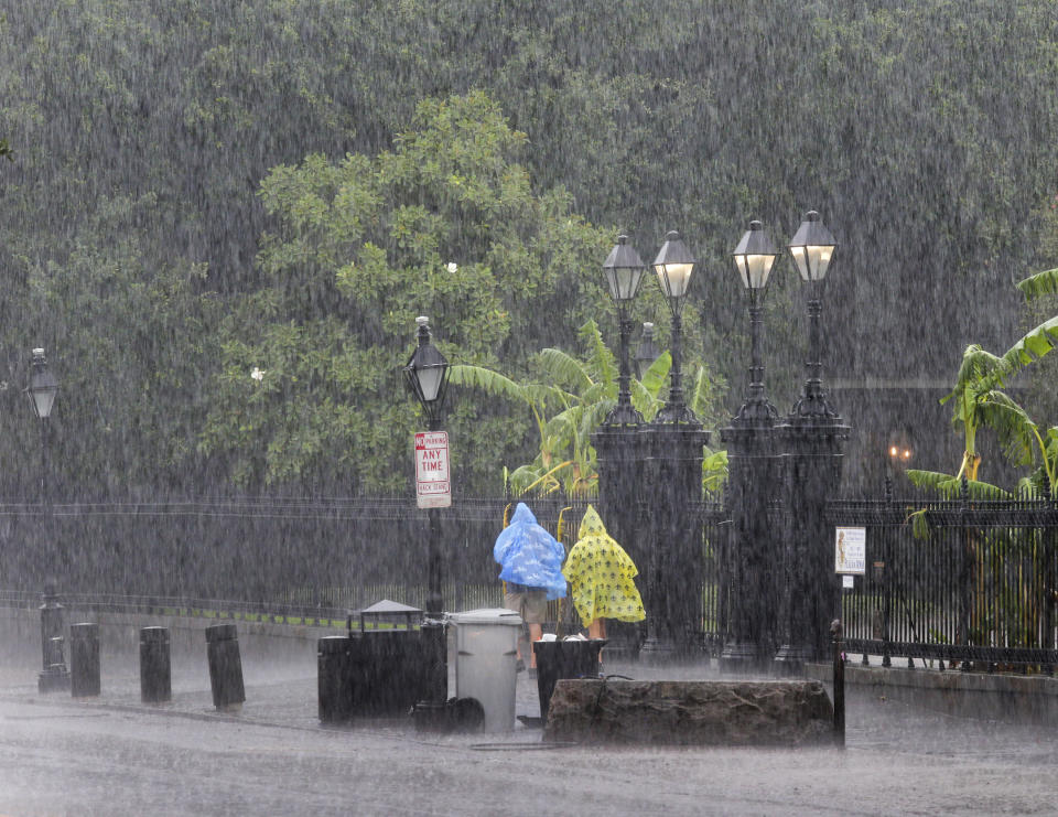 People walk on a street during a downpour at the French Quarter in New Orleans, Sunday, July 14, 2019. Tropical Depression Barry dumped rain as it slowly swept inland through Gulf Coast states Sunday, sparing New Orleans from a direct hit but stoking fears elsewhere of flooding, tornadoes, and prolonged power outages. (David Grunfeld/The Advocate via AP)