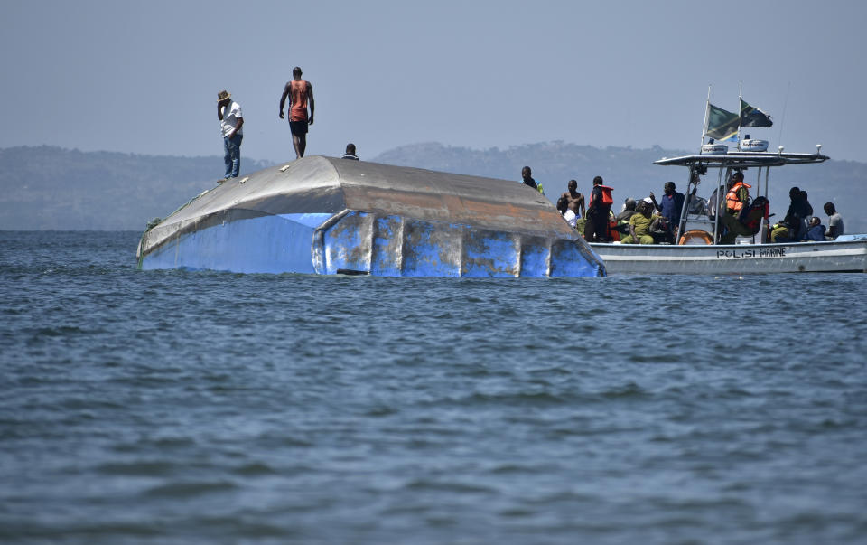 Rescue workers observe the capsized MV Nyerere passenger ferry as it lies upturned near Ukara Island, Tanzania Sunday, Sept. 23, 2018. Burials started Sunday of the more than 200 people who died when the ferry capsized on Lake Victoria, while the country's Defense Minister said no further survivors were likely to be found and search efforts had ended. (AP Photo/Andrew Kasuku)