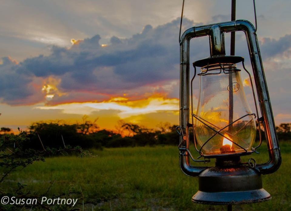 The sun sets on the plains. These lanterns are placed around the area we meet for sundowners. They serve to light our little group's cocktail hour as well as ward off any nearby predators.   © Susan Portnoy