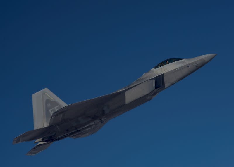 A U.S. Air Force F-22 Raptor, based out of Al Udeid Air Base, Qatar, flies alongside a KC-135 Stratotanker during an aerial refueling mission above an undisclosed location