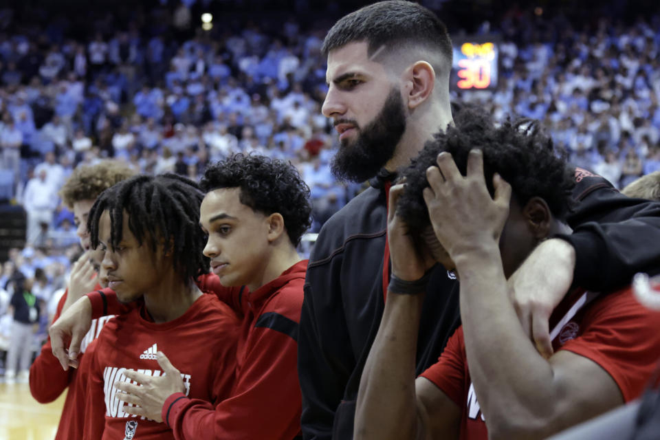 North Carolina State forward Dusan Mahorcic, second from right, and teammates react as medical personnel tend to injured player Terquavion Smith after Smith crashed to the floor after being fouled during the second half of an NCAA college basketball game against North Carolina, Saturday, Jan. 21, 2023, in Chapel Hill, N.C. (AP Photo/Chris Seward)
