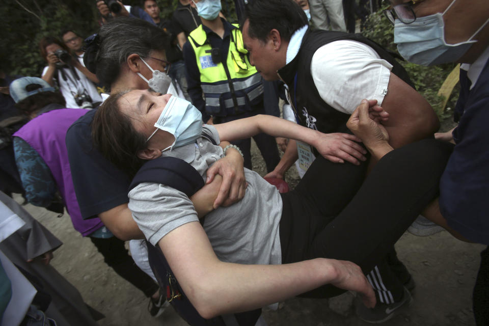 A distressed woman is carried away as families mourn for the victims in a train accident near Taroko Gorge in Hualien, Taiwan on Saturday, April 3, 2021. The train partially derailed in eastern Taiwan on Friday after colliding with an unmanned vehicle that had rolled down a hill, killing and injuring dozens. (AP Photo/Chiang Ying-ying)