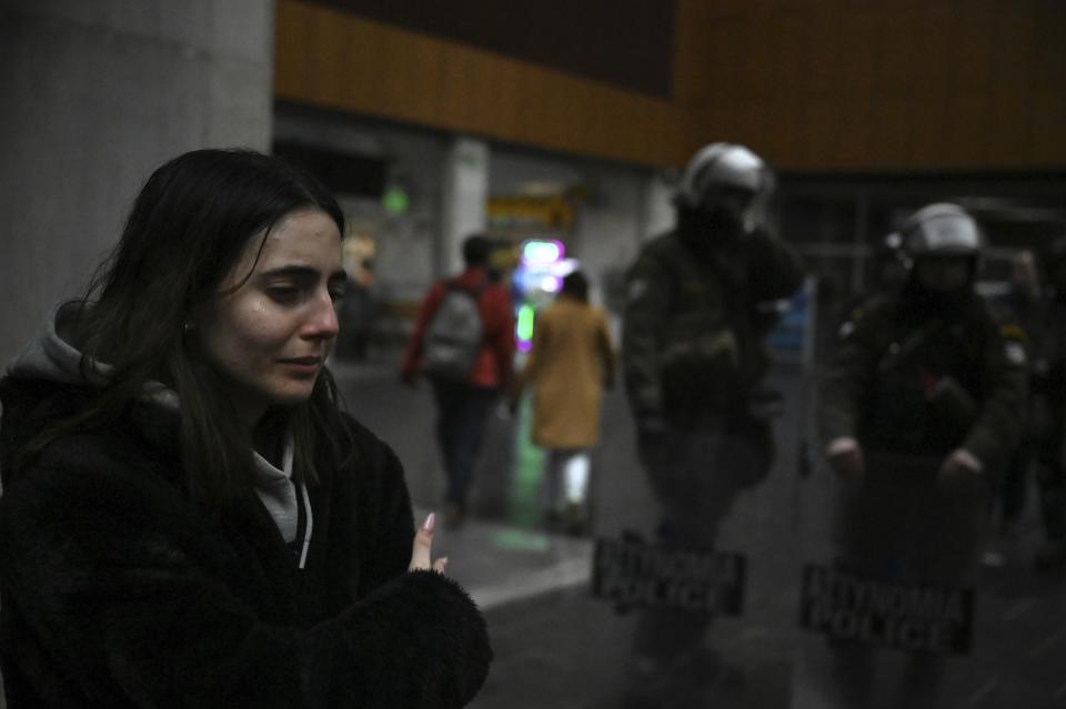 A young woman cries as she stands next to flowers and candles, in memory of the victims of the trains' collision, at the train station in the port city of Thessaloniki, northern Greece, Thursday, March 2, 2023. Emergency crews inched through the mangled remains of passenger carriages in their search for the dead from Tuesday night's head-on collision, which has left dozens passengers dead in Greece's worst recorded rail accident. (AP Photo/Giannis Papanikos)