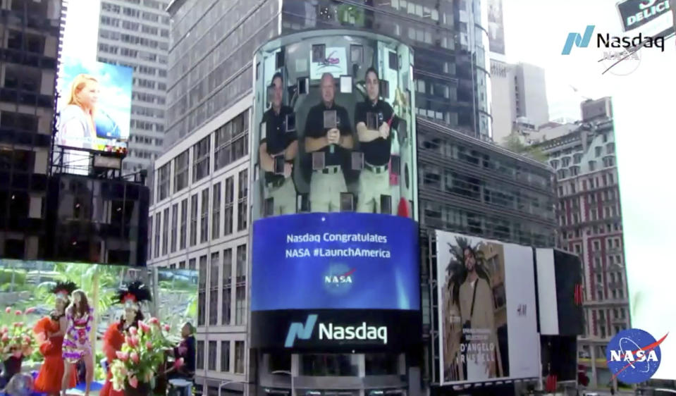 CORRECTS TO NASDAQ, NOT NEW YORK STOCK EXCHANGE - This image from video made available by NASA shows a live video of astronaut Chris Cassidy, right, ringing the opening bell of the Nasdaq Stock Exchange from the International Space Station, accompanied by fellow astronauts Robert L. Behnken, left, and Doug Hurley, broadcast on the exterior of the Nasdaq building Tuesday, June 2, 2020, in New York. (NASA via AP)