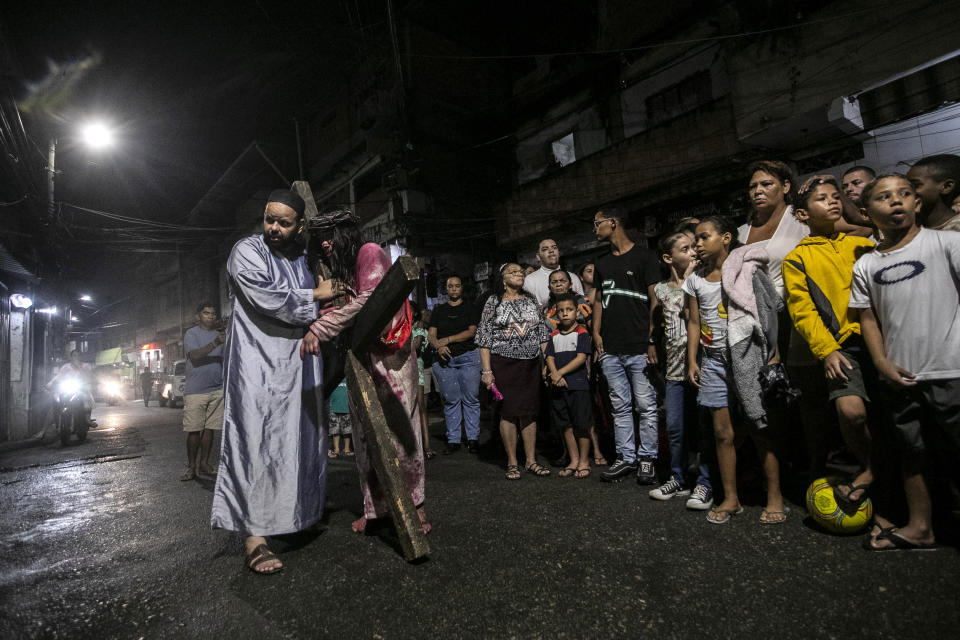 Luiz Henrique, playing the role of Jesus Christ, is helped to carry his cross during a Way of the Cross reenactment as part of Holy Week celebrations, at the Complexo do Alemao favela in Rio de Janeiro, Brazil, Friday, March 29, 2024. Holy Week commemorates the last week of Jesus Christ's earthly life which culminates with his crucifixion on Good Friday and his resurrection on Easter Sunday. (AP Photo/Bruna Prado)