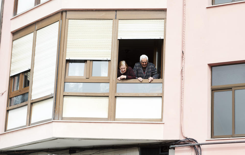 Dos personas mayores se asoman a la calle desde la ventana de su domicilio en Santander. (Foto: Juan Manuel Serrano Arce / Europa Press / Getty Images).