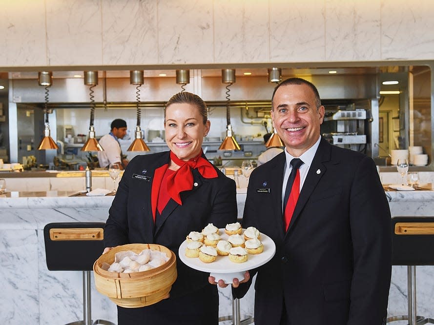 Qantas first-class lounge concept with two staff holding food.