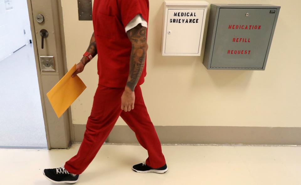 A detainee walks past boxes to file medical grievances during a 2019 media tour of an ICE detention center in Tacoma, Washington.