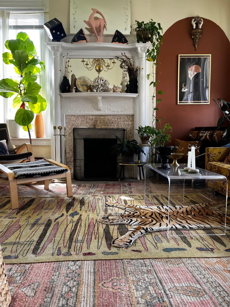 Pale yellow record room with fireplace, potted plant, acrylic coffee table, and patterned area rugs.