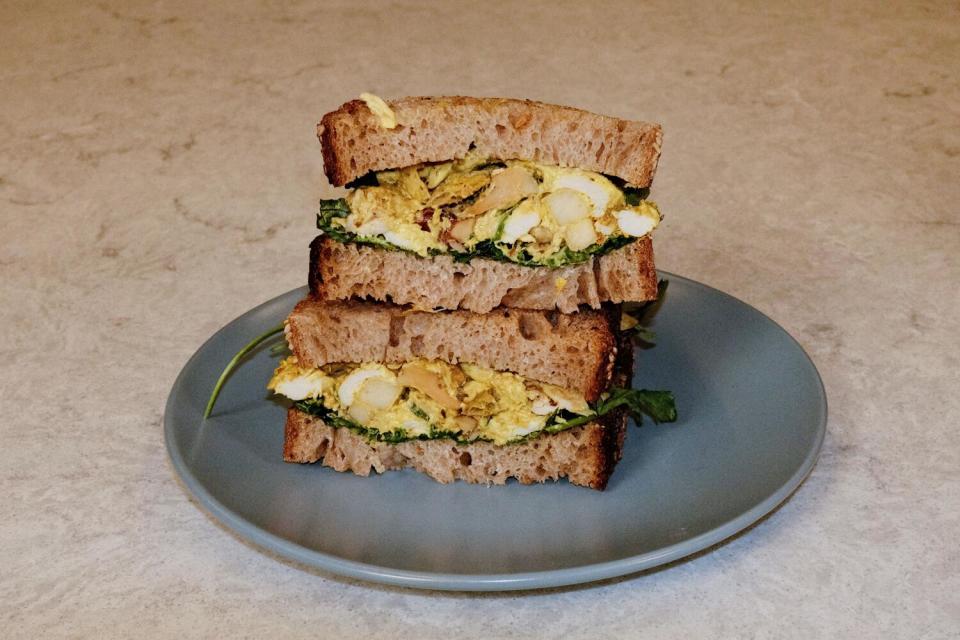 Two halves of a stacked curried chicken salad sandwich