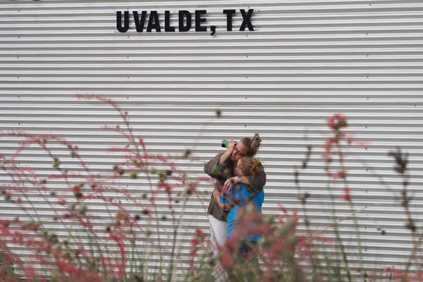 A woman cries and hugs a young girl while on the phone outside the Willie de Leon Civic Center in Uvalde, Texas, where a teenage gunman killed 19 young children and two adults in a shooting at an elementary school there on Tuesday. A new book suggests that communities can use potential attackers’ “observable warning behaviors” to prevent future shootings. (Allison Dinner/AFP via Getty Images)