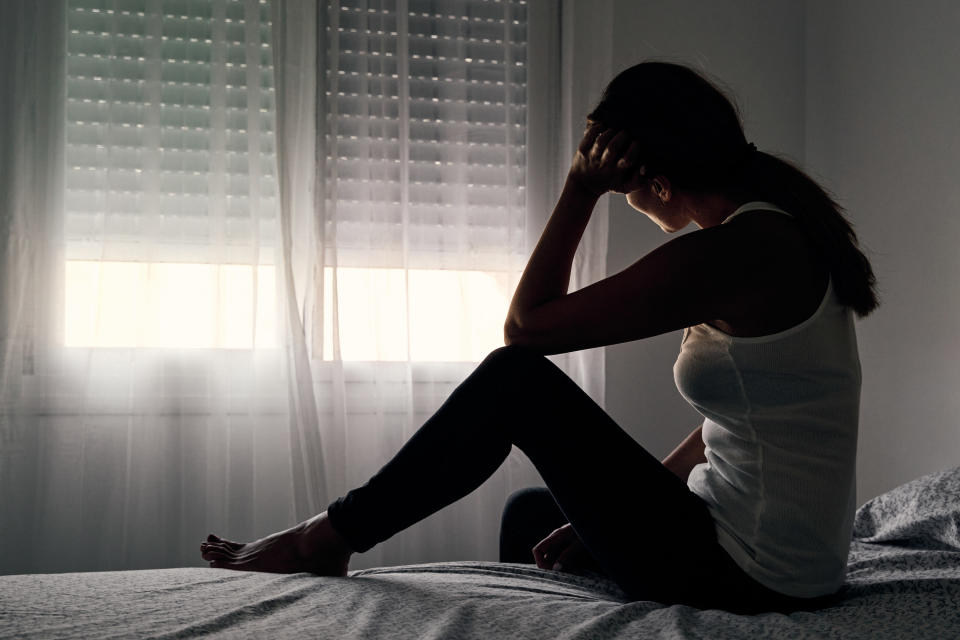 A woman sitting on a bed and looking out the window