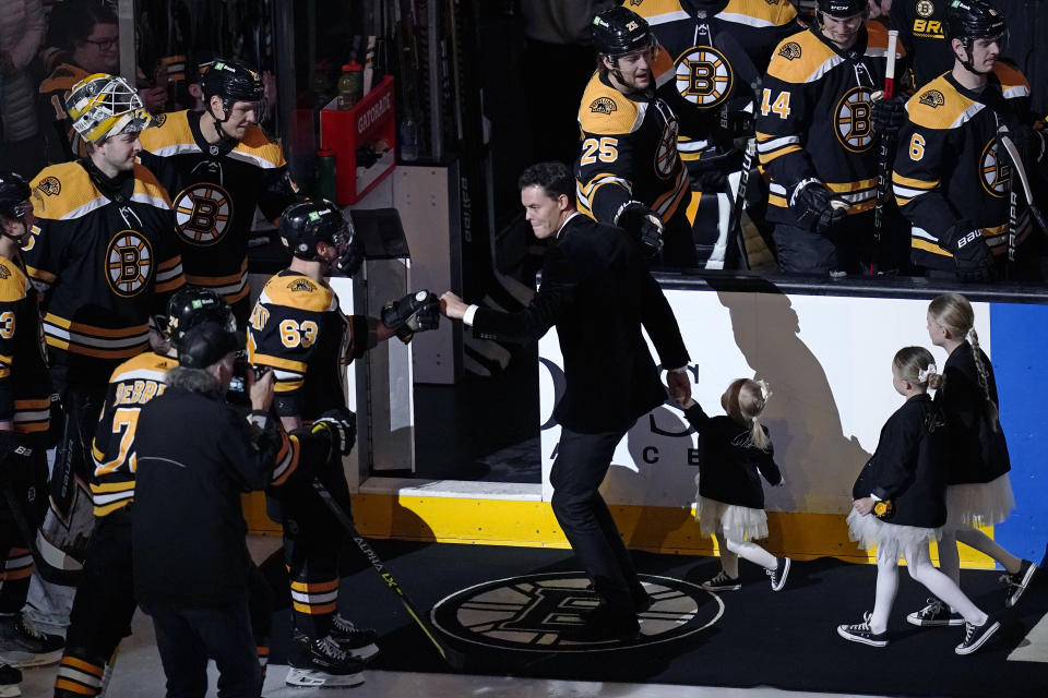 Former Boston Bruins goalie Tuukka Rask, center, is congratulated by Boston Bruins left wing Brad Marchand (63) during a ceremony honoring his retirement, before the team's NHL hockey game against the New Jersey Devils, Thursday, March 31, 2022, in Boston. With Rask are his three daughters, Livia, Adelie, and Vivien, from left. (AP Photo/Charles Krupa)