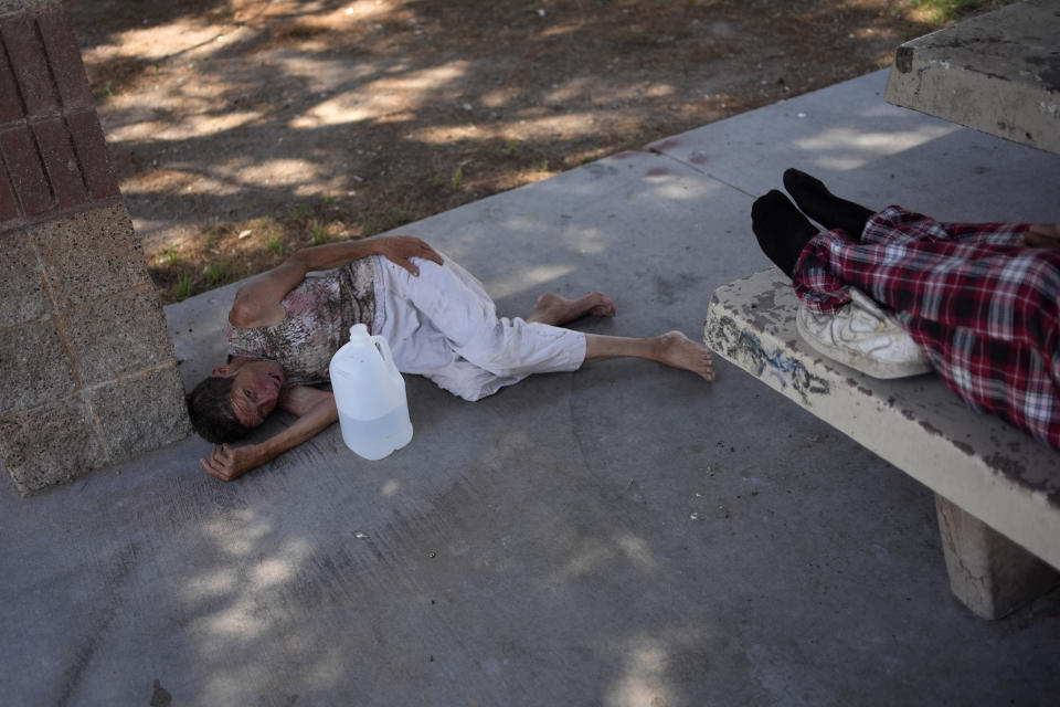 Deb Billet, 66, lies on the ground while Henderson Public Response officers call an ambulance to take her to the hospital for heat-related symptoms Wednesday, July 10, 2024, in Henderson, Nev. Billet has been living on the street. (AP Photo/John Locher)