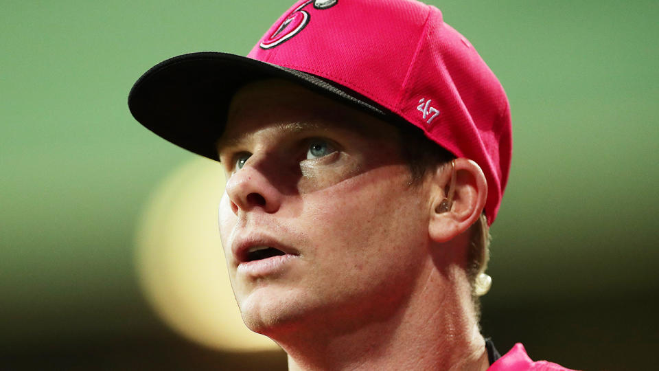 Steve Smith looks upwards while wearing a Sydney Sixers cap.