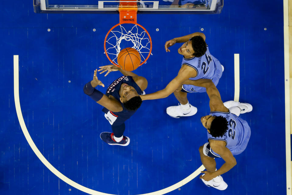 Connecticut's Josh Carlton, left, shoots the ball with Villanova's Jeremiah Robinson-Earl, center, and Jermaine Samuels, right, defending during the first half of an NCAA college basketball game Saturday, Jan. 18, 2020, in Philadelphia. (AP Photo/Chris Szagola)