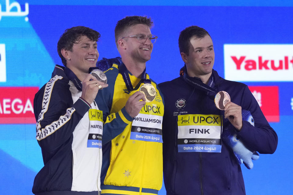 Gold medalist Sam Williamson of Australia, center, silver medalist Nicolo Martinenghi of Italy and bronze medalist Nic Fink of the United States pose for a photo during the medal ceremony for the men's 50-meter breaststroke final at the World Aquatics Championships in Doha, Qatar, Wednesday, Feb. 14, 2024. (AP Photo/Lee Jin-man)
