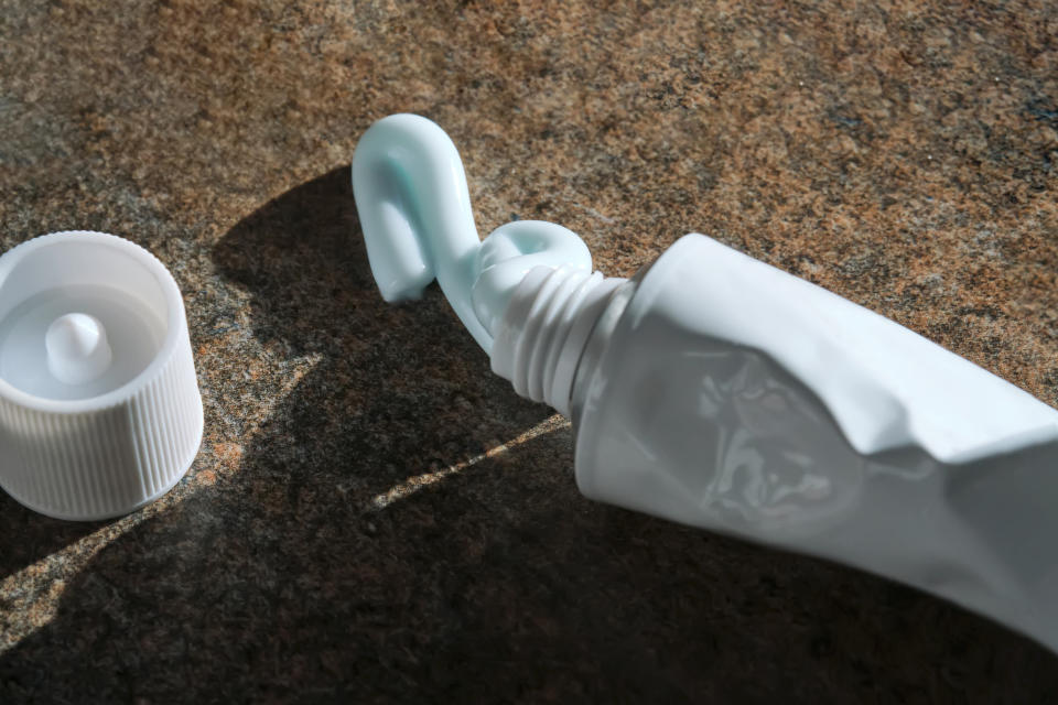 A squeezed toothpaste tube with paste oozing out onto a countertop