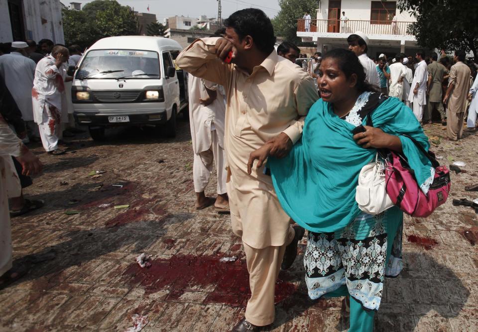 A man and woman mourn the death of their relatives at the site of a blast at a church in Peshawar