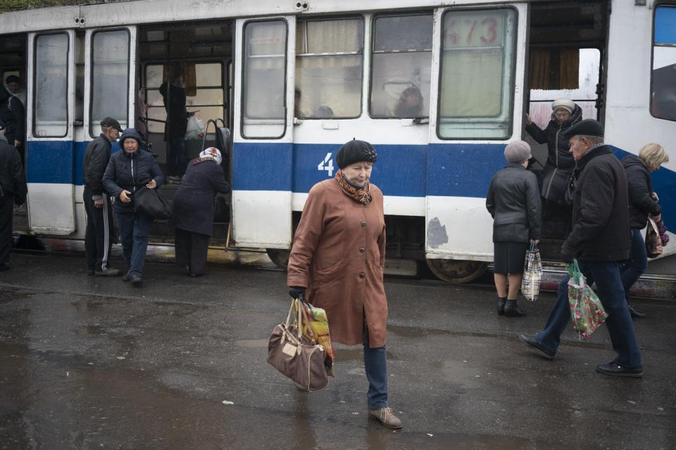 In this photo taken on Monday, April 15, 2019, a woman walks past a tram in Kryvyi Rih, in eastern Ukraine. The country votes Sunday, April 21, on whether to return President Petro Poroshenko for another 5-year term, or go with Volodymyr Zelenskiy, an actor and comedian native to Kryvyi Rih. (AP Photo/Evgeniy Maloletka)