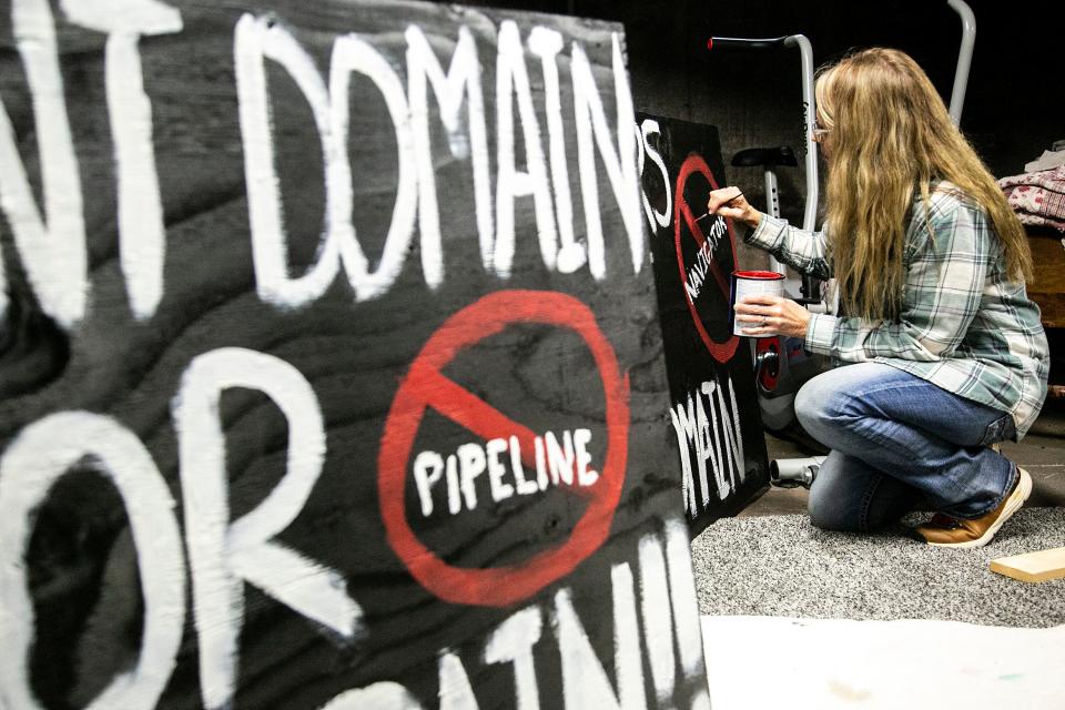 Karmin McShane paints a sign in opposition to a carbon capture and sequestration pipeline Dec. 14, 2021, in Linn County.