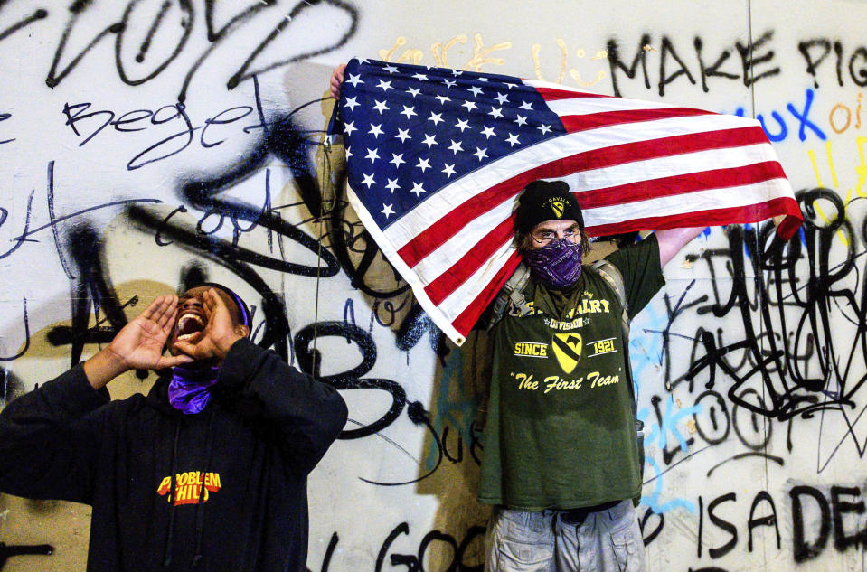 Black Lives Matter protesters gather at the Mark O. Hatfield United States Courthouse on Tuesday, July 21, 2020, in Portland, Ore. Demonstrators removed portions of the boarding, which cover the building's ground floor, before federal officers used chemical irritants and rubber bullets to disperse them. (AP Photo/Noah Berger)