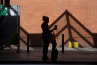 A passenger stands outside Atocha rail station after arriving by taxi in Madrid, Spain, Saturday, Oct. 3, 2020. Madrid has started its first day under a partial lockdown with police controlling travel in and out of the Spanish capital. Spain's largest city has become the continent's biggest hot spot for the second wave of the coronavirus. The measures, affecting 4.8 million people, prohibit all nonessential trips in and out of the capital and nine of its suburbs. (AP Photo/Paul White)