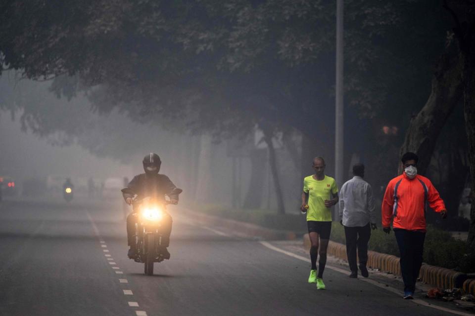A man runs along a street amid smoggy conditions in New Delhi (AFP via Getty Images)