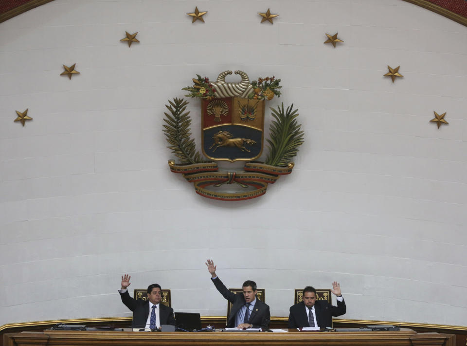 Juan Guaido, center, President of National Assembly and self-proclaimed interim president, Edgar Zambrano first Vice President, left, and Staling Gonzalez second Vice President, raise their hands to approve of daily order of business during a session of the National Assembly in Caracas, Venezuela, Tuesday, April 2, 2019. Venezuela's chief justice on Monday asked lawmakers of the rival pro-government National Constituent Assembly to strip Guaido of his parliamentary immunity, taking a step toward prosecuting him for alleged crimes as he seeks to oust President Nicolas Maduro.(AP Photo/Fernando Llano)