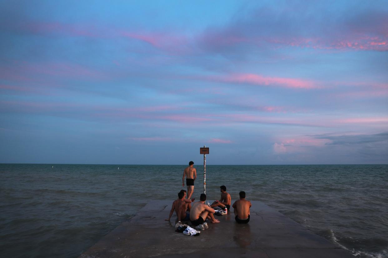 People hang out on a wharf next to the Strait of Florida during the seasonal king tides on October 26, 2019 in Key West, Florida. Researchers estimated that the Florida Keys will likely see increased flooding as sea levels continue to rise due to various factors including global warming.