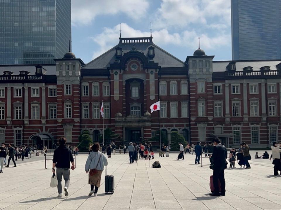 Tokyo Station with Japanese flag waving in wind.