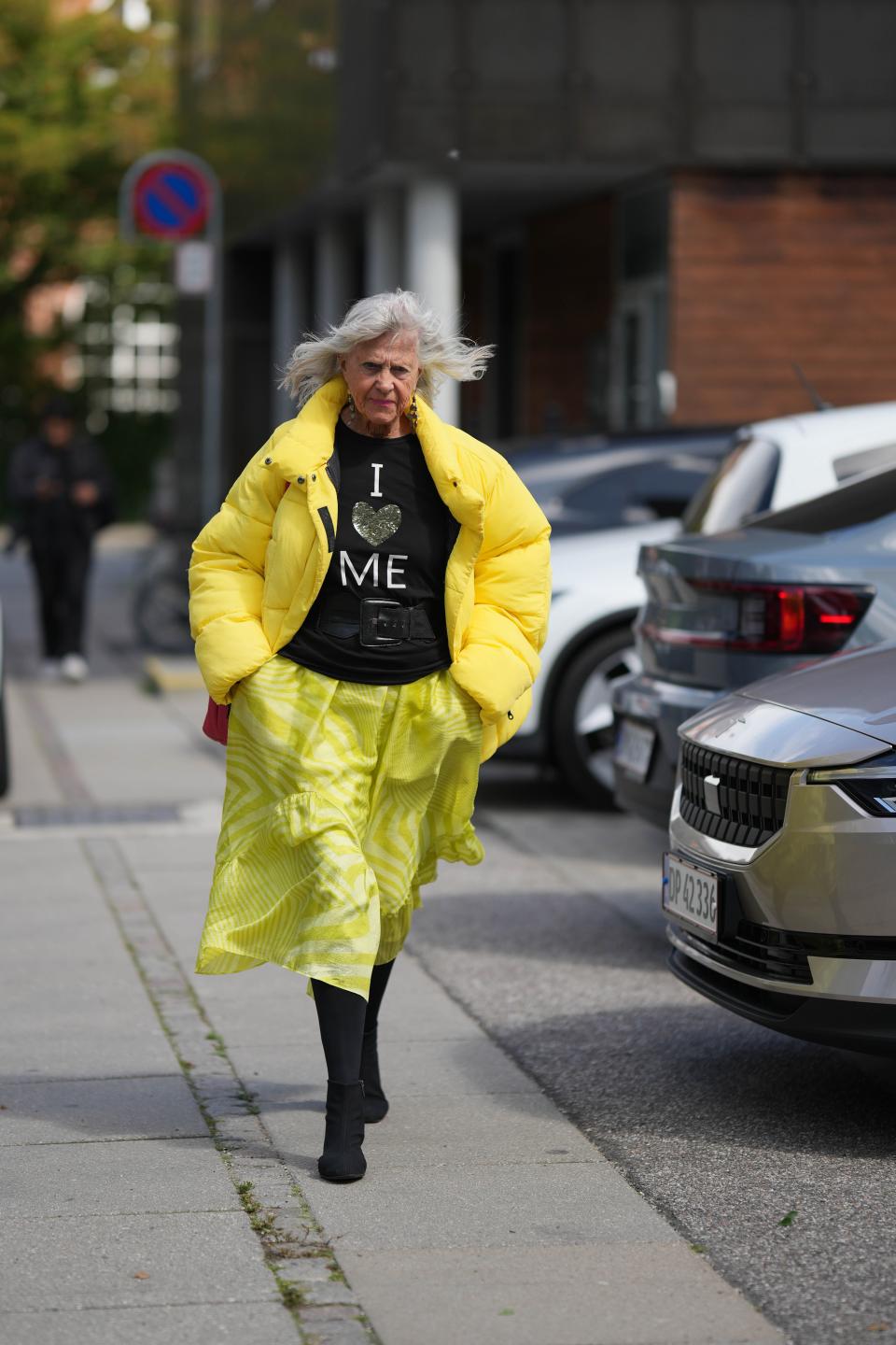 A guest of the Stamm fashion show wearing a graphic t-shirt with yellow puffer jacket and yellow zebra print skirt