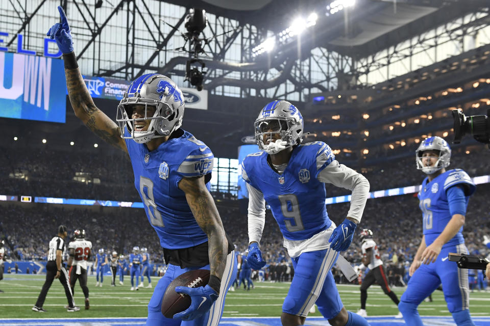 Detroit Lions wide receiver Josh Reynolds (8) passes teammates Jameson Williams (9) and Jared Goff (16) after scoring a touchdown against the Tampa Bay Buccaneers during the first half of a divisional round game in the NFL postseason on Sunday, Jan. 21. Celebrated with.  , 2024, in Detroit.  (AP Photo/Jose Juarez)