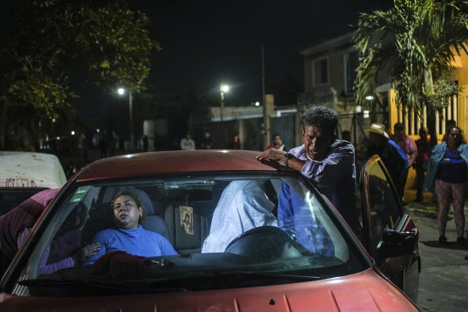 Erika Maria Cruz, left, and her husband, grieve next to the body of their son, Brando Arellano Cruz, fatally shot by police after he failed to pull over, in Lerdo de Tejada, Mexico, Saturday, Jan. 19, 2024. Four municipal police officers are under investigation in relation to the death of the young man, after the victim's neighbors staged violent protests and attempted to lynch the officers. (AP Photo/Felix Marquez)