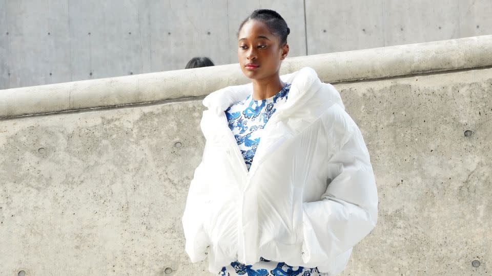 A guest at one of Friday's shows wears a padded coat over a blue-and-white patterned dress. - Kahyun Lee/CNN