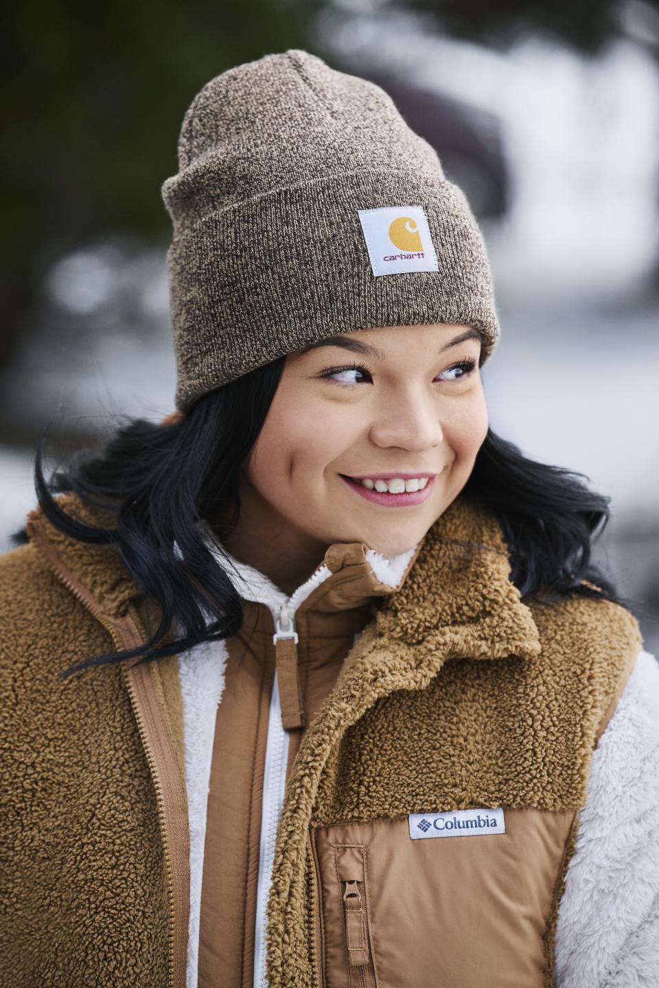 A close up of a smiling woman in a Columbia fleece vest and Carhartt toque