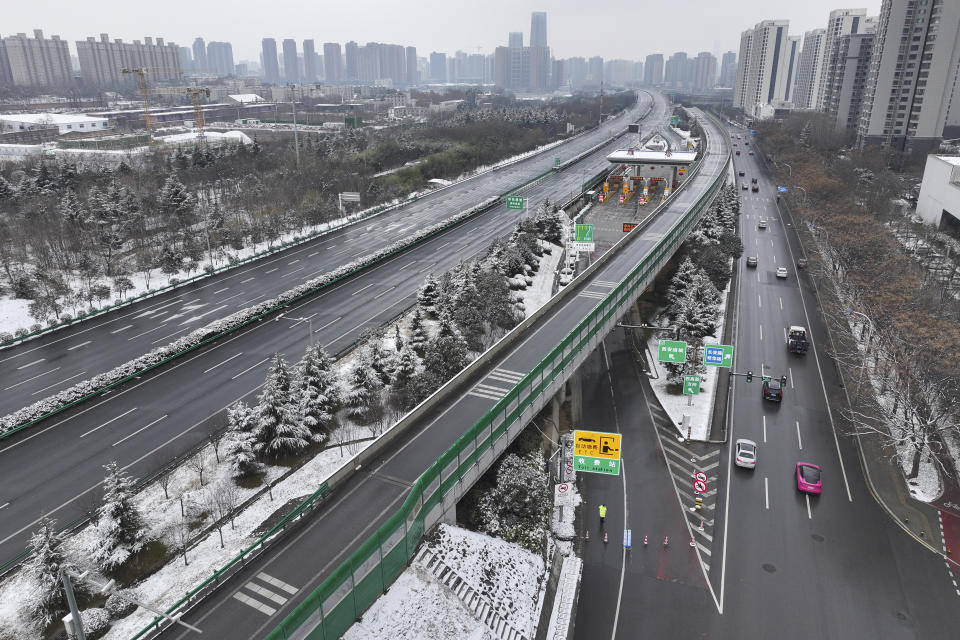 Motorists move past a worker, center bottom, standing guard on a closed ramp of an expressway following a snowfall in Xi'an in northwest China's Shaanxi province, Wednesday, Feb. 21, 2024. Heavy snow has blanketed northern and central China, disrupting traffic and forcing schools to cancel classes. (Chinatopix Via AP)